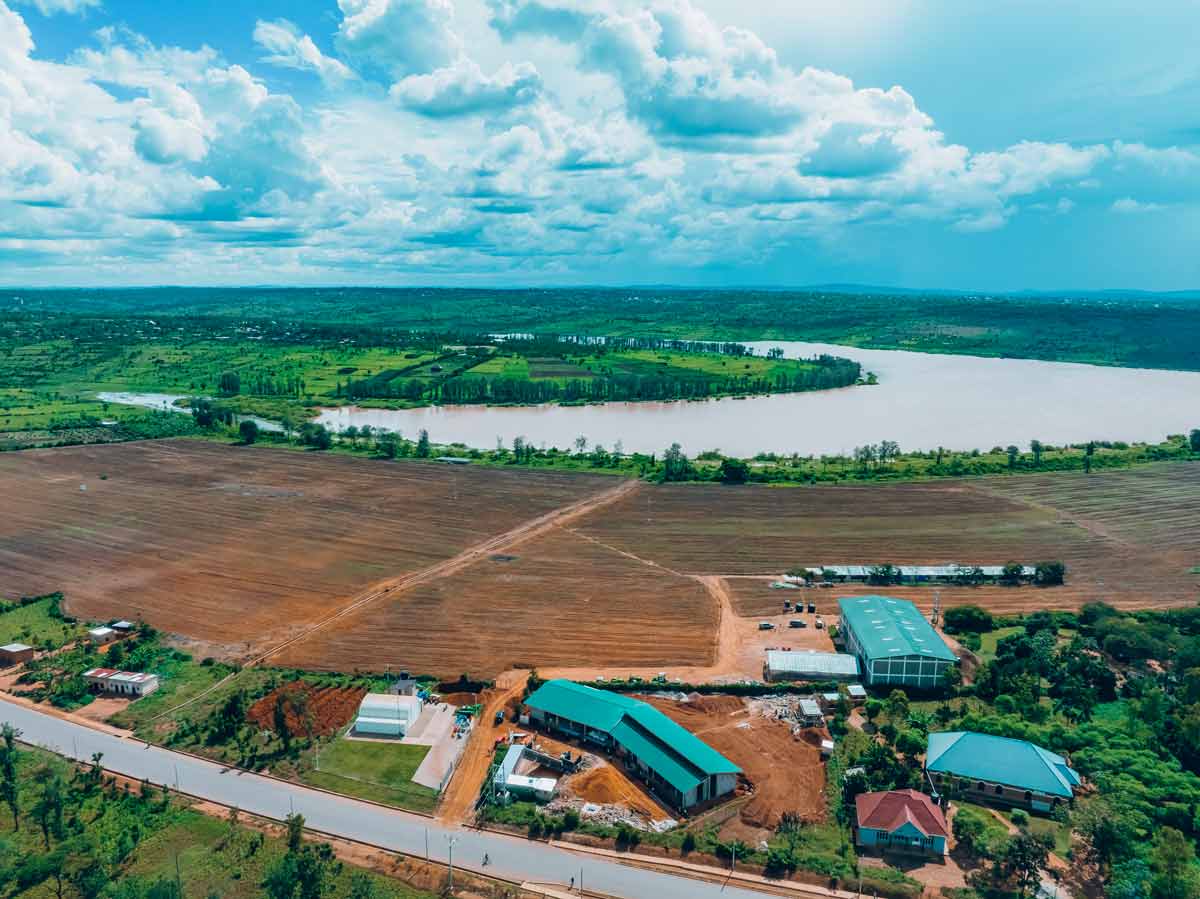 Aerial view of ARC Power’s commercial and industrial development site near a river in Rwanda, surrounded by farmland and green landscape