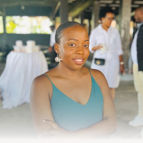 Marie Louise Niyigena, Community Liaison Officer at ARC Power Rwanda, standing with arms crossed and smiling in a light-filled indoor space